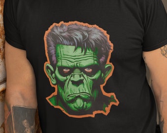 May include: A black t-shirt with a green monster face graphic. The monster has a furrowed brow and a serious expression.