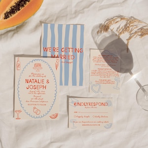 May include: Wedding stationery suite featuring a papaya half on a white surface. The suite includes a main invitation, a card with the text "We're Getting Married", and a response card. The invitations have red and blue accents.
