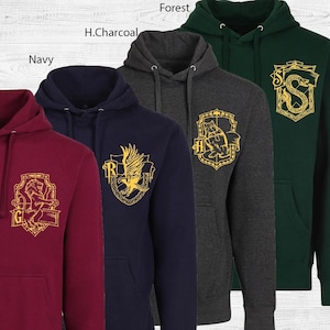 May include: A collection of hooded sweatshirts in various colors: burgundy, navy, charcoal, and forest green. Each hoodie features a different gold crest design on the front, with the names of the colors printed above the hoodies.