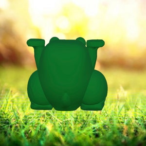 May include: A green frog figurine with a smooth, rounded surface. The frog is sitting on a bed of green grass.