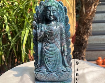 May include: A standing Buddha statue carved from mottled blue and green stone with red inclusions. The figure features a raised right hand, a draped robe, and a lotus base. A vertical line indicates a height of 9 inches and a width of 4 inches.
