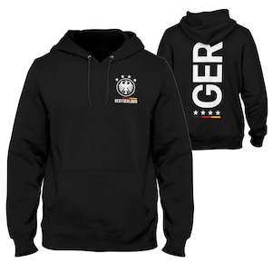 Könnte beinhalten: Schwarzes Kapuzenpullover mit einem weißen deutschen Adler-Logo und dem Wort "DEUTSCHLAND" auf der Vorderseite. Die Rückseite des Pullovers trägt das Wort "GER" in Weiß mit drei weißen Sternen und den Farben der deutschen Flagge.