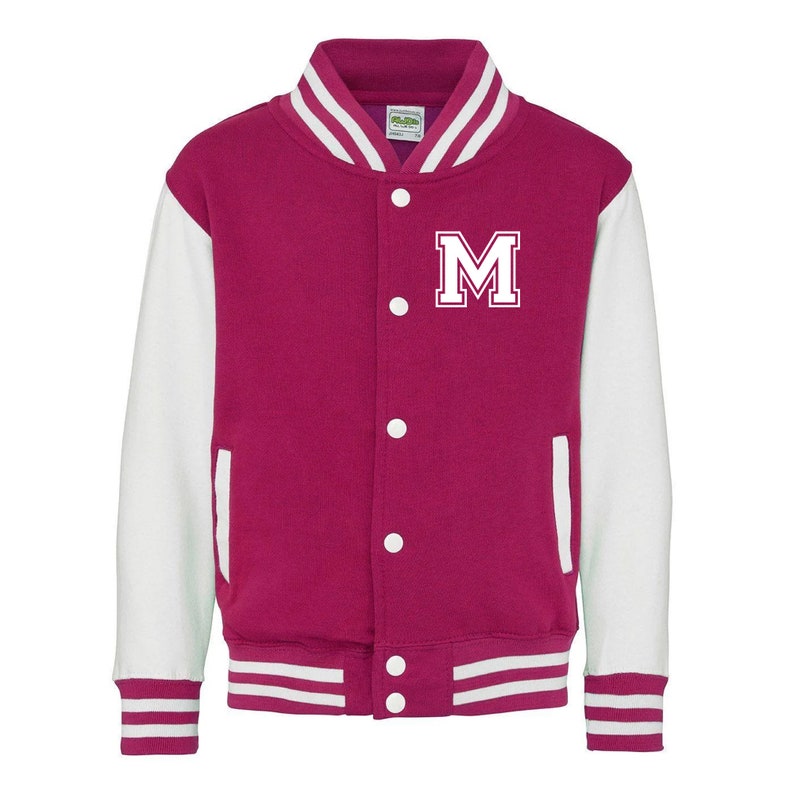Pu&ograve; includere: Una giacca da baseball rosa e bianca con una lettera "M" bianca sul davanti. La giacca ha un colletto bianco e maniche bianche con una striscia rosa ai polsini e in basso.