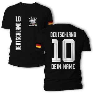 Könnte beinhalten: Ein schwarzes T-Shirt mit dem deutschen Bundesadler, dem Schriftzug DEUTSCHLAND und der Nummer 10 auf der Vorderseite. Die Rückseite zeigt den Schriftzug DEUTSCHLAND, die Nummer 10 und DEIN NAME, mit kleinen deutschen Flaggen an den Ärmeln.