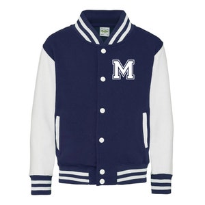 Pu&ograve; includere: Una giacca da baseball blu navy e bianca con una lettera "M" bianca sul davanti. La giacca ha un colletto, polsini e cintura a costine.