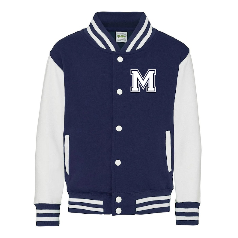 Pu&ograve; includere: Una giacca da baseball blu navy e bianca con una lettera "M" bianca sul davanti. La giacca ha un colletto, polsini e cintura a costine.