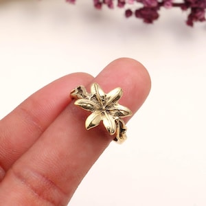 以下が含まれることがあります： 詳細な花の模様が施されたゴールドカラーのリング。 リングの花の要素は6つの花びらがあり、繊細なバンドにセットされています。 リングは指に表示され、そのサイズと形状を強調しています。