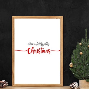 May include: A framed print with the text "Have a holly jolly Christmas" in red and black lettering on a white background. A small potted Christmas tree with gold baubles is in the foreground.