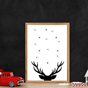 May include: A framed print featuring a black silhouette of a deer head with antlers against a white background. The deer head is surrounded by small black stars.