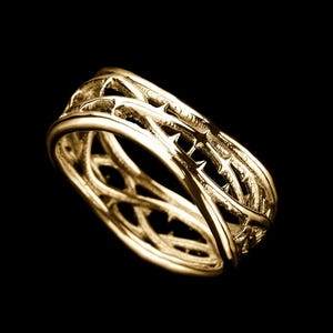 May include: A gold ring with a detailed design of intertwined thorns. The ring is a statement piece with a unique and intricate design.