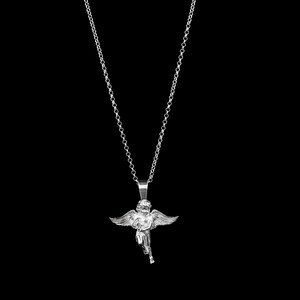 May include: A silver-colored pendant necklace featuring a detailed angel with outstretched wings. The angel is suspended from a delicate chain against a black background. The necklace is a piece of jewelry.