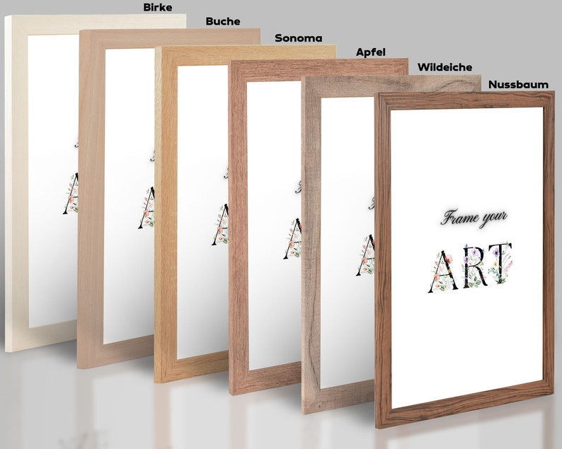 May include: Six different wood picture frames in various shades of brown, from light to dark. The frames are arranged in a row from left to right, with the lightest frame on the left and the darkest frame on the right. The frames are all the same size and shape, and they all have a simple, clean design. The frames are labeled with the names of the wood types: Birke, Buche, Sonoma, Apfel, Wildeiche, and Nussbaum. The text "Frame your ART" is visible in the center of the image.