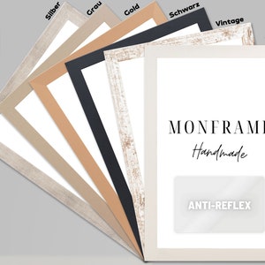 Könnte beinhalten: Ein Set aus sechs Bilderrahmen in verschiedenen Farben, darunter Silber, Grau, Gold, Schwarz, Weiß und Vintage. Die Rahmen sind alle aus Holz und haben ein schlichtes, elegantes Design. Die Rahmen sind fächerförmig angeordnet, wobei der größte Rahmen unten und der kleinste Rahmen oben ist. Die Rahmen sind alle mit ihrer Farbe beschriftet. Der größte Rahmen trägt den Text "MONFRAME Handmade" und "ANTI-REFLEX", der darauf gedruckt ist.