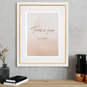 Könnte beinhalten: Ein weißer Bilderrahmen mit goldener Einfassung, der einen rosa-weißen Aquarellhintergrund mit goldenem Glitzer und dem Text "Frame your story" zeigt.