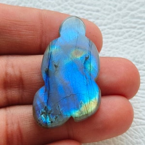 Op de afbeelding: Een blauwe en groene labradorit edelsteen met een iriserende glans. De edelsteen heeft de vorm van een wolk en een glad, gepolijst oppervlak.
