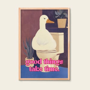 Könnte beinhalten: Gerahmter Kunstdruck mit einer weißen Ente auf einer Toilette. Die Ente hat einen orangefarbenen Schnabel und befindet sich in einem Badezimmer mit Pflanzen. Der rosa Text lautet "good things take time".