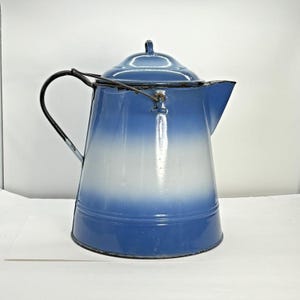 May include: A vintage blue and white enamel teapot with a black handle and a wire lid holder.