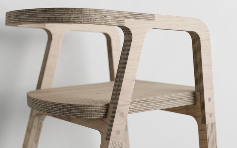May include: A wooden high chair with a rounded seat and back, made from plywood with visible layers. The chair has a simple, modern design with rounded edges.