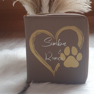 Könnte beinhalten: Eine graue Reißverschlusstasche mit einem goldenen Herz und einem Pfotenabdruck. Der Text "Simba & Romeo" ist in Weiß im Herzen geschrieben.