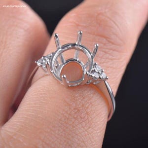 May include: A silver ring setting with a round centre stone and small diamonds on the band.