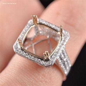 Puede incluir: Un anillo de plata con un engaste de forma cuadrada rodeado de pequeños diamantes. El engaste está diseñado para sujetar una piedra preciosa grande. La banda del anillo también está decorada con pequeños diamantes.
