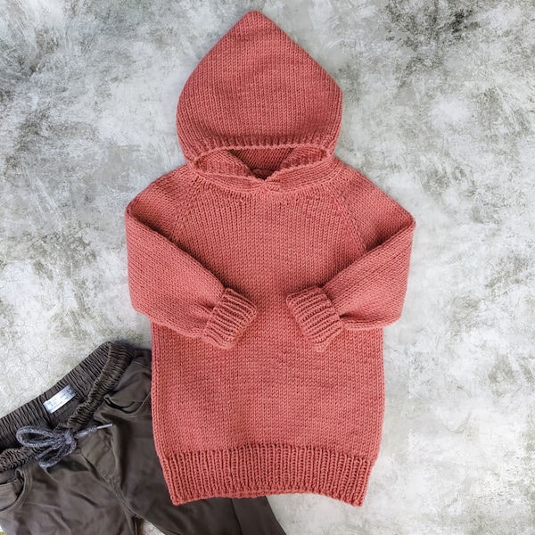 May include: A coral pink knitted hooded sweater with long sleeves and a ribbed hem.