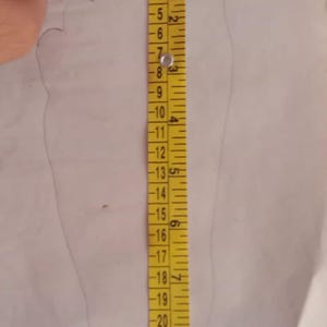 May include: A yellow measuring tape with black markings is placed next to a pencil outline of a foot. The tape measures up to 28 inches.