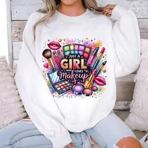 May include: White sweatshirt with a colorful graphic design of makeup items and the text "Just a Girl Who Loves Makeup".