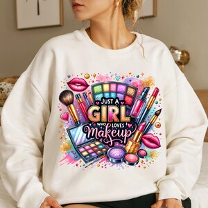 May include: White sweatshirt with a colorful graphic design featuring makeup brushes, lipstick, eyeshadow palettes, and the text "Just a Girl Who Loves Makeup".