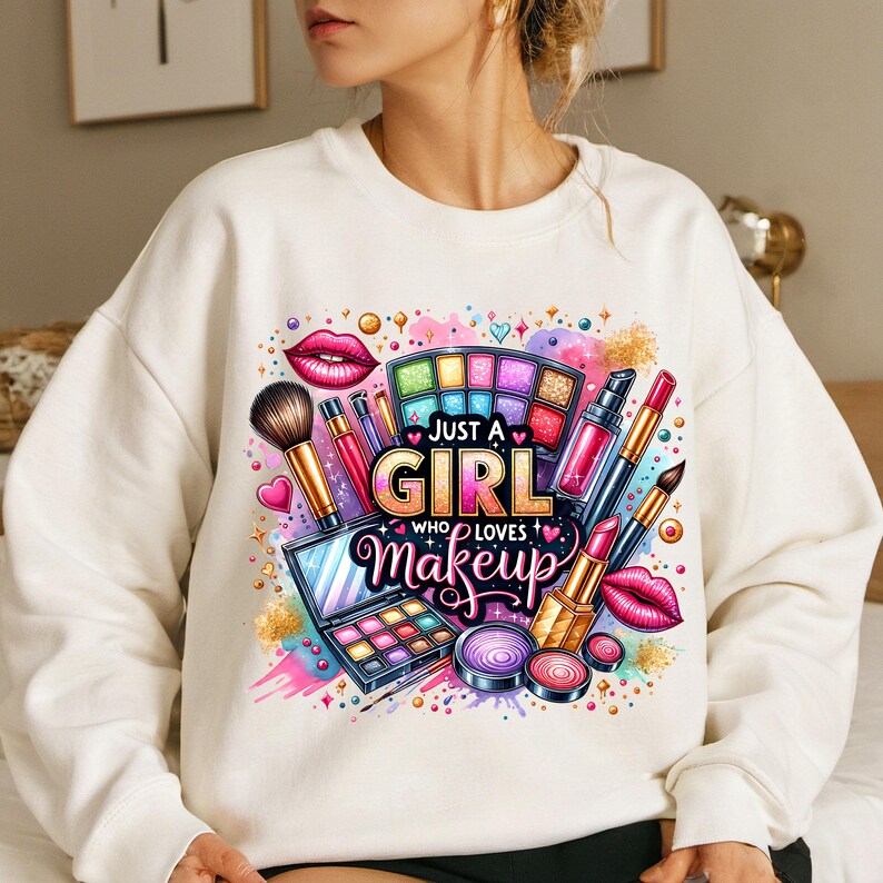 May include: White sweatshirt with a colorful graphic design featuring makeup brushes, lipstick, eyeshadow palettes, and the text "Just a Girl Who Loves Makeup".