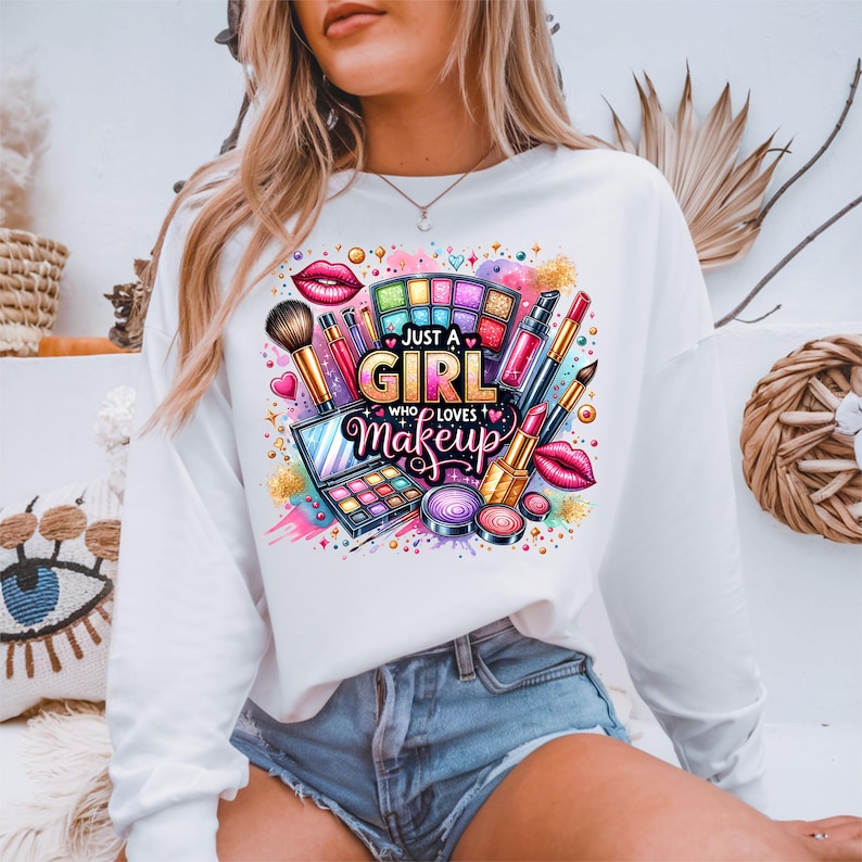 May include: White long-sleeve sweatshirt with a colorful graphic design of makeup products and the text "Just a Girl Who Loves Makeup".
