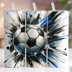 May include: A white tumbler with a football design. The design features a football in the center, surrounded by a burst of black, blue, and white paint splatters. The tumbler has a straw.