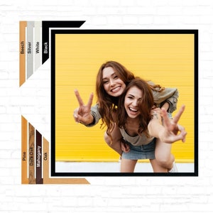 May include: Two women are smiling and making peace signs with their hands. They are standing in front of a bright yellow wall. The woman at the back is wearing a grey shirt and the woman at the front is wearing a grey shirt and a denim skirt.