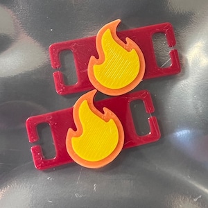 May include: Two red plastic slider buckles with yellow and orange flame designs.