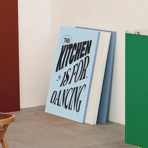 Puede incluir: Un armario de cocina verde con una encimera de mármol y un cartel que dice "This Kitchen Is For Dancing" en letras negras y blancas sobre un fondo azul claro.