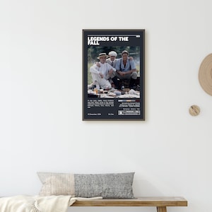 Op de afbeelding: Een zwart-wit poster voor de film "Legends of the Fall". De poster toont een foto van drie mannen die op een picknickdeken in een bosrijke omgeving zitten. De poster bevat ook de titel van de film, de releasedatum en de leeftijdsclassificatie.