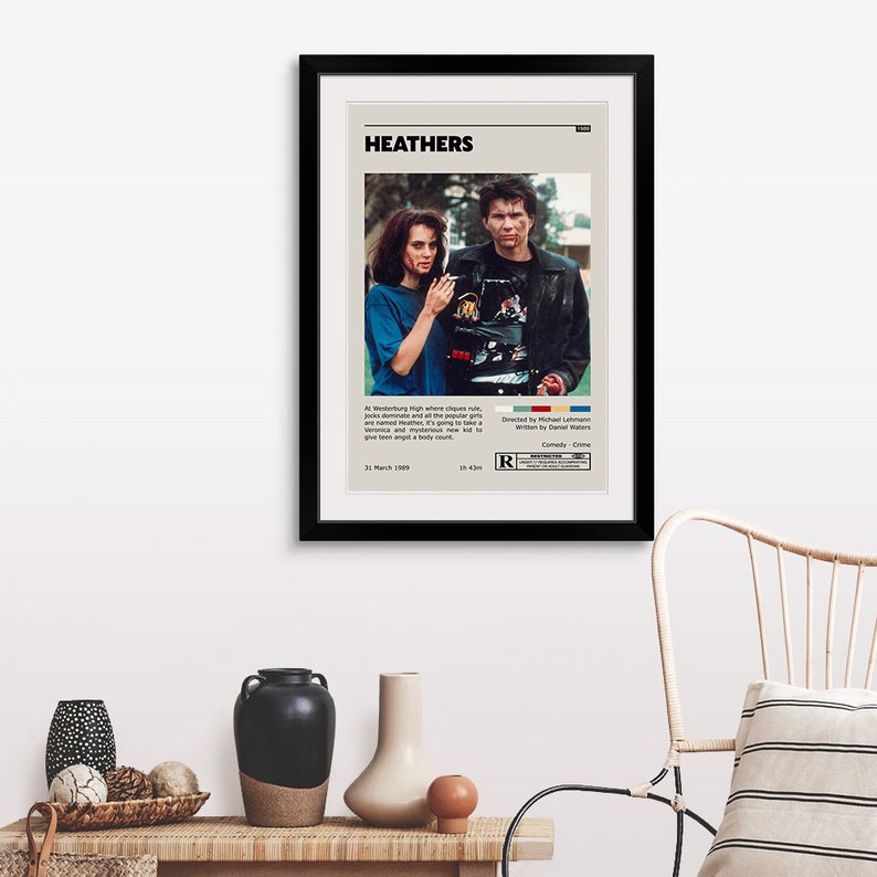 May include: A movie poster for the film "Heathers" featuring Winona Ryder and Christian Slater. The poster is black and white with a red "R" rating. The text on the poster reads "Heathers", "Directed by Michael Lehmann", "Written by Daniel Waters", "Comedy Crime", "1st March 1989", "1h 43m".