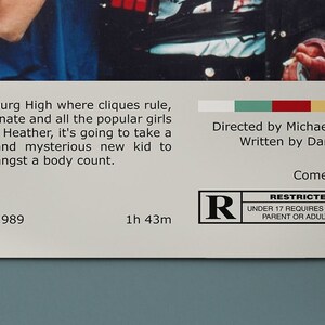 May include: Movie poster for the 1989 film Heathers. The poster features a photo of two teenagers, a boy and a girl, holding a gun. The poster is in a retro style with a white background and red, blue, and yellow accents. The text on the poster reads "Heathers" and "31 March 1989".