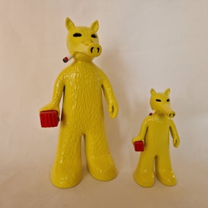 Puede incluir: Dos figuritas de animales de dibujos animados amarillas con hocicos largos. La figurita más grande sostiene un ladrillo rojo en su mano derecha y tiene un cigarrillo blanco en su boca. La figurita más pequeña sostiene un ladrillo rojo en su mano derecha.