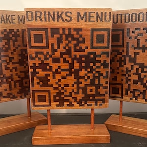 May include: Three rectangular wooden signs on stands, each featuring a dark brown laser-engraved QR code and text. The left sign reads DOWNYFLAKE M, the center sign reads DRINKS MENU, and the right sign reads OUTDOOR MENU, all with a smooth finish.
