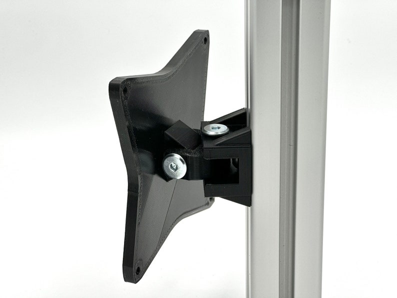 May include: Black plastic monitor mount with a silver metal pole. The mount is attached to the pole with screws. The mount is designed to hold a monitor.