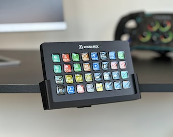 May include: A black Stream Deck with a variety of coloured buttons, each with a different icon. The Stream Deck is mounted on a desk.