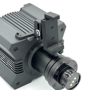 May include: Black camera with a black phone mount attached to the side. The camera has a black lens and a black dial with arrows on it.