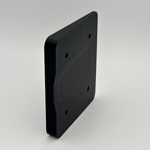 May include: Black plastic wall mount with four screw holes and a curved edge.