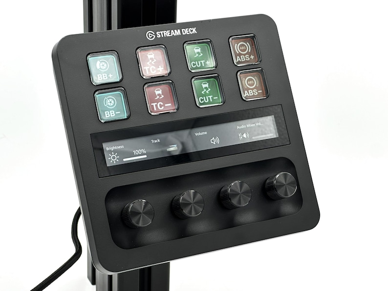 May include: A black Stream Deck with a screen displaying "Audio Mixer Vol." and a slider. The deck has eight buttons with icons and labels: "BB+", "TC+", "CUT", "ABS+", "BB-", "TC-", "CUT-", "ABS-". There are three knobs below the screen.