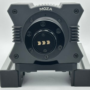 May include: A black MOZA camera stabilizer with a silver base and a black control knob with a directional arrow indicator.