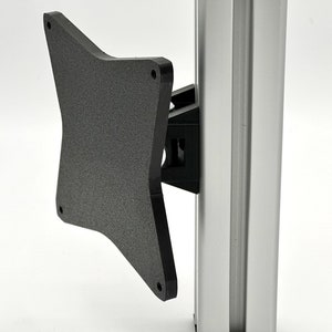 May include: A black plastic monitor mount bracket with a textured surface. The bracket is attached to a silver pole.