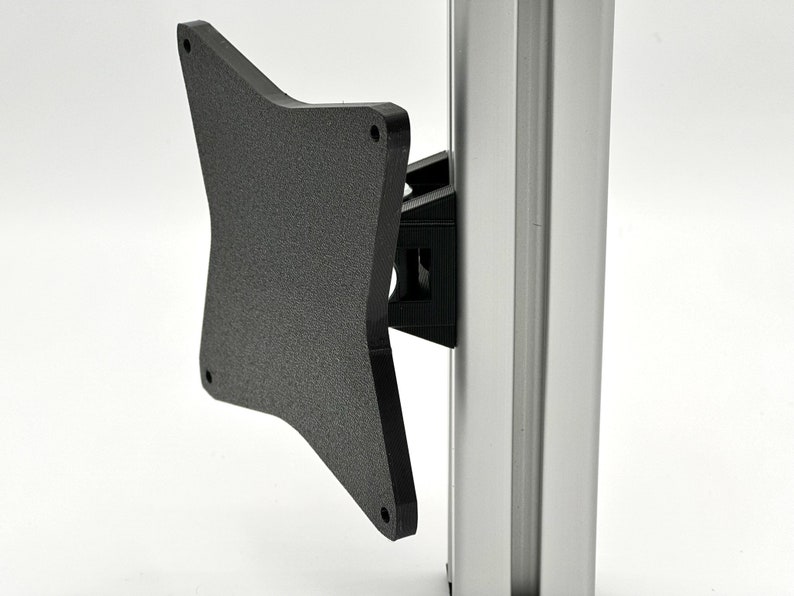 May include: A black plastic monitor mount bracket with a textured surface. The bracket is attached to a silver pole.