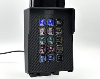 May include: A black control panel with a carbon fiber texture, featuring multiple illuminated buttons. The buttons are labeled with symbols and text, including "VOL+", "ABS+", "CUT+", "TC+", and "BB+". The panel is designed for automotive or electronic use.
