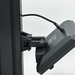 May include: A black camera monitor mounted on a black metal pole with a black cable connected to the back.
